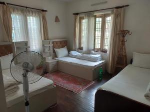 a small room with two beds and a fan at Nepal christian guest house in Pātan