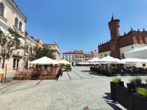 a street with tables and umbrellas in a city at Apartamenty na Rynku Tarnów in Tarnów