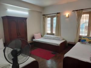 a room with two beds and a fan and windows at Nepal christian guest house in Pātan
