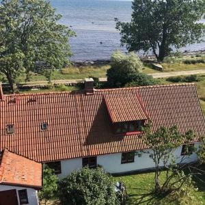 une maison blanche avec des toits rouges et l'océan dans l'établissement Norrekås Beach Studios, à Borrby