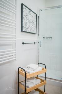 La salle de bains est pourvue d'une douche et d'une étagère avec des serviettes. dans l'établissement Harmony Boutique Hotel, à Drawsko Pomorskie