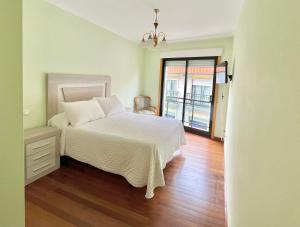 een slaapkamer met een wit bed en een houten vloer bij Apartamento Bellavista in Portonovo