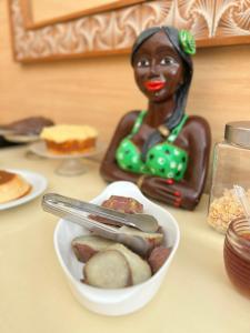 una mesa con un tazón de comida con una figurita de mujer en Pousada Pangea Tropical en Arraial d'Ajuda