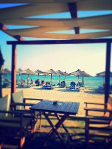 una mesa de picnic en una playa con sillas y sombrillas en Summer Sea Family House+Yard, en Sozopoli