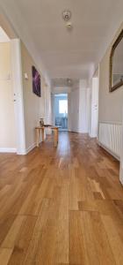 an empty room with a wooden floor and a table at Linksway House in Birkenhead