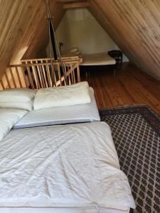 1 dormitorio con cama con sábanas blancas y escalera en Norrekås Beach Studios en Borrby
