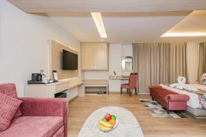 a living room with a bed a couch and a bowl of fruit at Regenta Inn Luxinna Heights Mcleodganj in Dharamshala