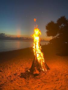 a bonfire on the beach with the sunset in the background at NEW CORALs in Gili Trawangan