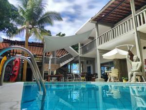 a swimming pool in front of a house at Pousada Água de Fuego in Maragogi