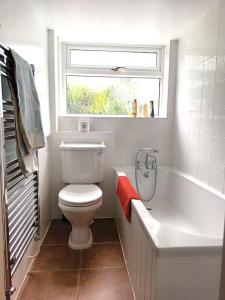 a bathroom with a toilet and a tub and a window at Period Cottage near Suffolk Coast and Forest in Tunstall +22 photos