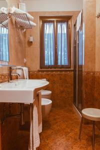 bagno con lavandino, servizi igienici e specchio di Hotel Patriarchi a Aquiléia