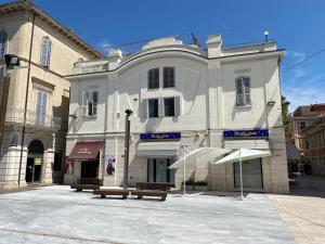 a white building with benches in front of it at Appartamentino In Piazza in Grottammare