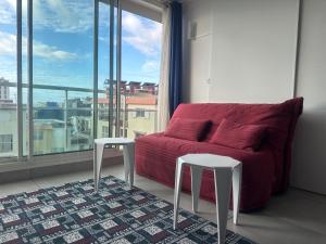 a living room with a red couch and two stools at Appartement T2 Colombier pour 5 personnes vue mer in Sainte-Clotilde