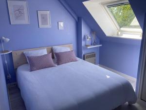 1 dormitorio azul con 1 cama grande con almohadas moradas en Maison familiale dans une rue paisible, en Gouville-sur-Mer