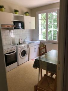 une cuisine avec un lave-linge et une table dans l'établissement Appartement bagnoles, à Bagnoles-de-l'Orne