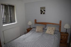 Upper Wood End Farm Holiday Cottages في Marston Moretaine: غرفة نوم بسرير ومخدات ومصباحين