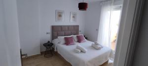 Schlafzimmer mit einem Bett mit rosa und weißen Kissen in der Unterkunft Ático - CENTRO de Sabinillas - Calle la Pasionaria - in San Luis de Sabinillas