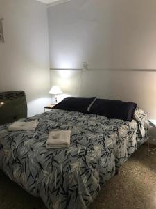 1 dormitorio con 1 cama con manta negra y gris en Boulevard Alsina 5 en San Antonio de Areco