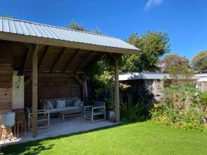 - un pavillon avec un canapé et des chaises dans un jardin dans l'établissement Air Beach & Sea Villa Unieke locatie, à Zandvoort