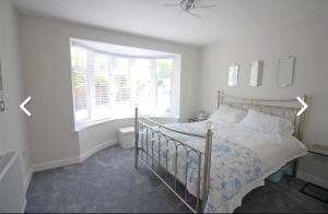 a white bedroom with a bed and a window at Kinghurst Lodge 5 minutes from the sea in Torquay