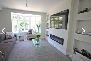 a living room with a couch and a tv on a wall at Kinghurst Lodge 5 minutes from the sea in Torquay