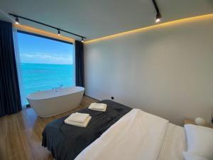 1 dormitorio con bañera y ventana grande con vistas al océano en Black Diamond Sevan, en Sevan