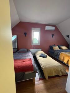 two beds in a room with red walls at Les Mottes in Gandelain