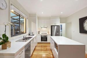 a large white kitchen with a sink and a refrigerator at Comfortable homestay in Clayton North