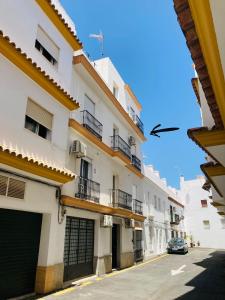 un edificio con balcones y un coche aparcado en una calle en Apartamento Luz de Conil. WIFI+A/C. SOLO FAMILIAS Y PAREJAS, en Conil de la Frontera