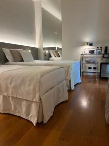 two beds in a room with wooden floors at Airport BEA Rooms in Azzano San Paolo