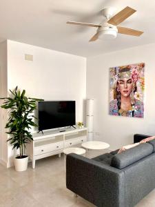 a living room with a couch and a flat screen tv at Apartamento Luz de Conil. WIFI+A/C. SOLO FAMILIAS Y PAREJAS in Conil de la Frontera