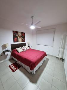 a bedroom with a red bed and a ceiling fan at Home in Río Cuarto +7 photos