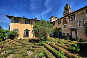 um grande edifício com um jardim em frente em Castello di Montegufoni by PosarelliVillas em Montagnana Val di Pesa