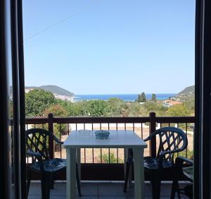 una mesa y sillas en un balcón con vistas al océano en Alexandros Rooms & Studios, en Skopelos Town