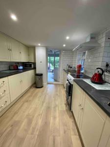 a kitchen with white cabinets and a wooden floor at Two rivers reach in Iford