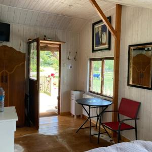 Zimmer mit einem Tisch, 2 Stühlen und einer Tür in der Unterkunft Domaine des Thyllères,Chalet Colvert in Beaufour