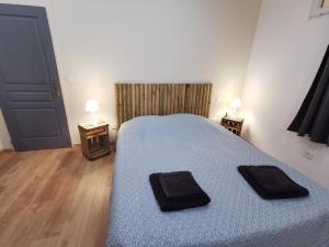 una camera da letto con un letto con due asciugamani neri di GÎTE 3* SAINT GUILHEM LE DESERT CHEZ MARIUS a Saint-Guilhem-le-Désert