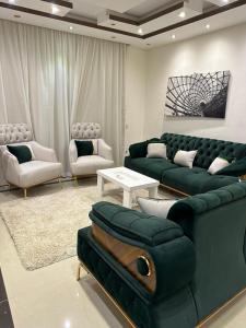 a living room with a green couch and chairs at شقة للايجار كمبوند زايد ديونز in Sheikh Zayed