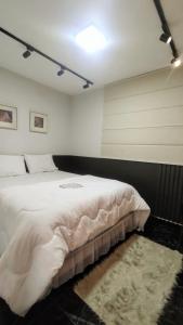 乌贝兰迪亚9 Andar - Estilo industrial Moderno e Aconchegante的卧室配有一张大白色的床和地毯