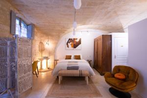 ein Schlafzimmer mit einem Bett und einem Stuhl in einem Zimmer in der Unterkunft La DAME de FLAUX in Uzès