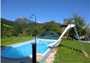 a swimming pool with a slide in a yard at Bunzbauernhof in Bad Mitterndorf