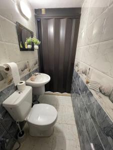 a white bathroom with a toilet and a sink at Beit Al Hasan بيت الحسن in Um Qeis