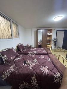 a bedroom with a bed with a purple comforter at Beit Al Hasan بيت الحسن in Um Qeis