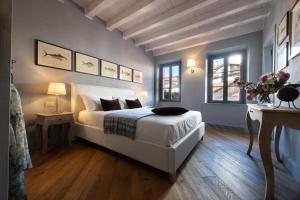 a bedroom with a bed and a table and two windows at Isola Bella Apartments - Via del Voltone in Stresa
