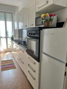 La cuisine est équipée de placards blancs et d'un réfrigérateur blanc. dans l'établissement Bnbook Trilo Malpensa, à Cardano al Campo