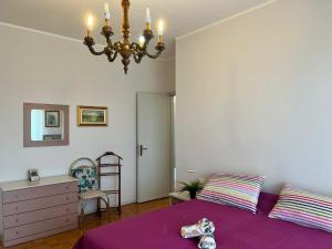 - une chambre avec un lit violet et un lustre dans l'établissement Bnbook Trilo Malpensa, à Cardano al Campo