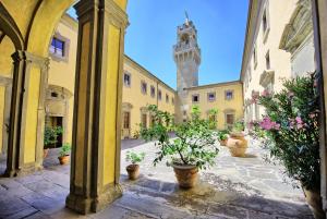 a courtyard with potted plants and a clock tower at Castello di Montegufoni by PosarelliVillas in Montagnana Val di Pesa