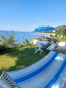 eine Hängematte mit einem Tisch und einem blauen Sonnenschirm in der Unterkunft Denize Sıfır 2 Yatak Odalı ve 2 Çekyatlı Bahçeli Ev - Seafront, 2 bedroom, 2 sofa bed house with big garden in Rize