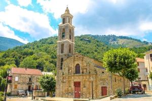 une ancienne église en pierre avec une tour d'horloge dans une ville dans l'établissement Maison de village, charmante et authentique, haute-corse, à Vezzani