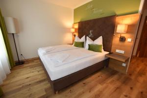 a bedroom with a large bed with white sheets and green pillows at Gasthof Lebzelter in Strasswalchen